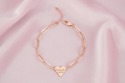 Rose gold bracelet with a heart-shaped tag on a white background